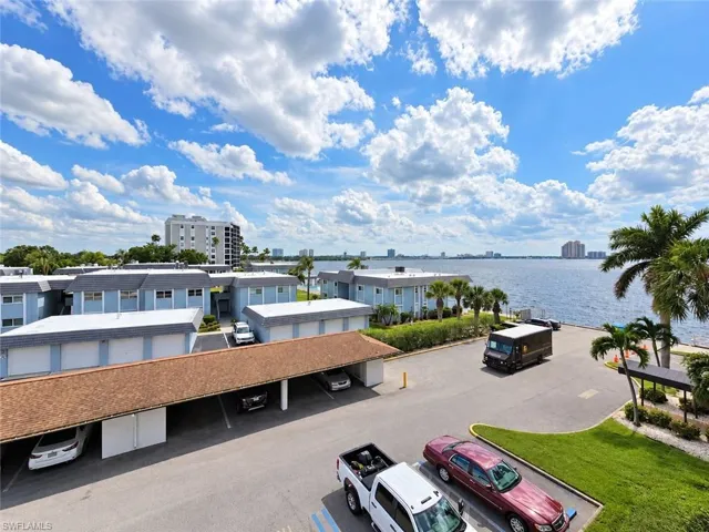 Waterfront setting with expansive water frontage, mature palm trees, and covered parking