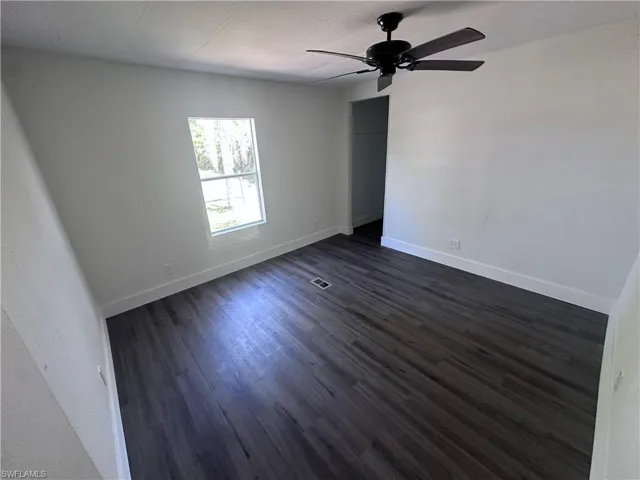 Empty room featuring dark wood-style flooring and a ceiling fan