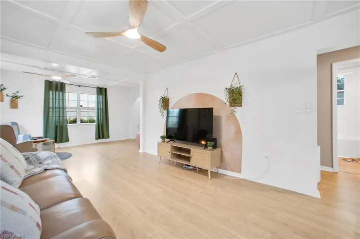Living room with a ceiling fan, wood finished floors, coffered ceiling, and plenty of natural light