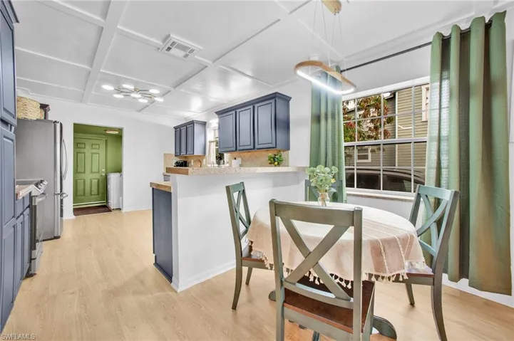 Kitchen with coffered ceiling, light wood-style floors, light countertops, a peninsula, and a chandelier