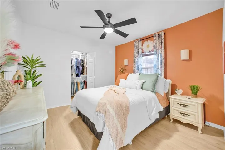 Bedroom featuring light wood-type flooring, a closet, baseboards, a ceiling fan, and a spacious closet