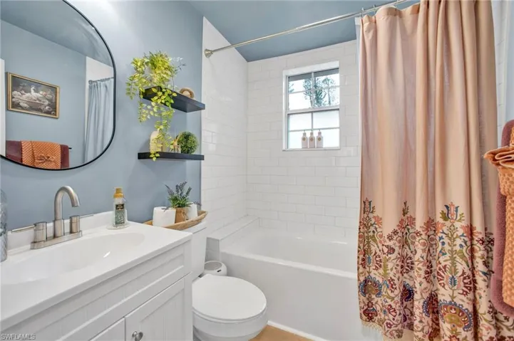 Full bath featuring vanity, shower / bathtub combination with curtain, and toilet