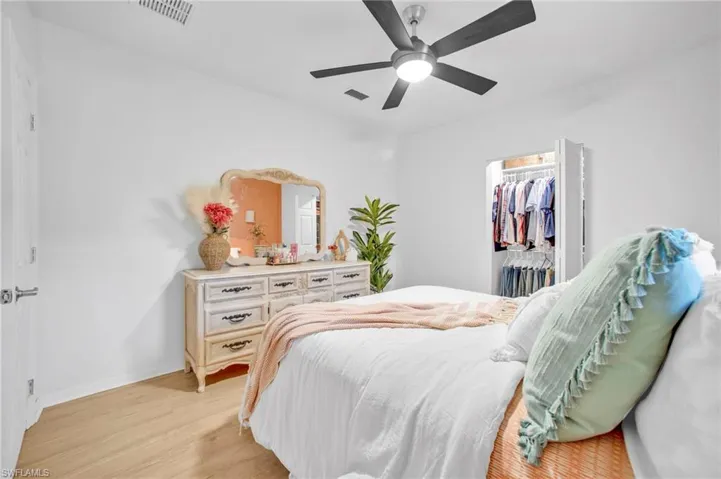 Bedroom with light wood finished floors, a closet, ceiling fan, baseboards, and a walk in closet