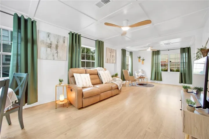 Living room featuring coffered ceiling, plenty of natural light, light wood-type flooring, and a ceiling fan