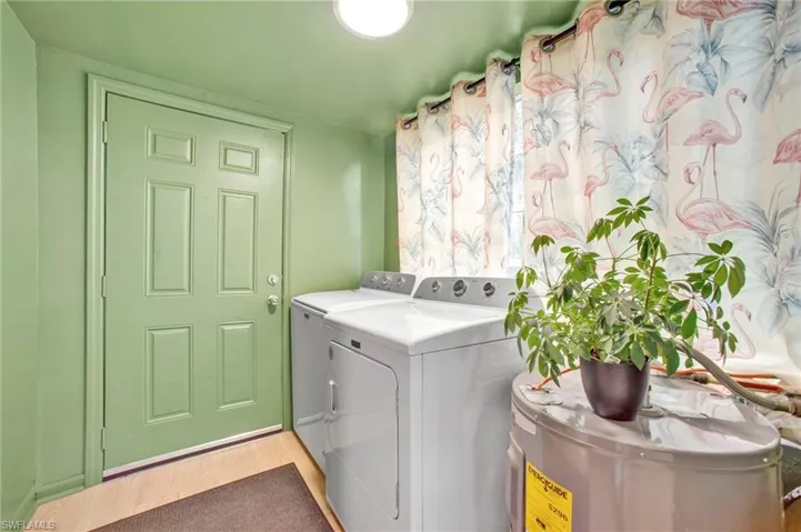 Laundry area with independent washer and dryer, light wood-style floors, and water heater