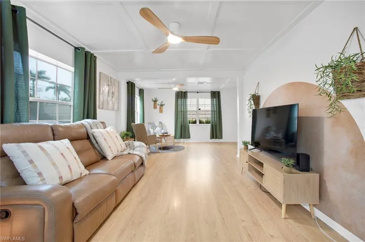Living area with light wood-style floors, ceiling fan, and coffered ceiling
