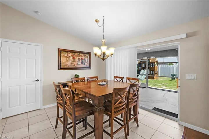 Tiled dining area featuring vaulted ceiling and a chandelier