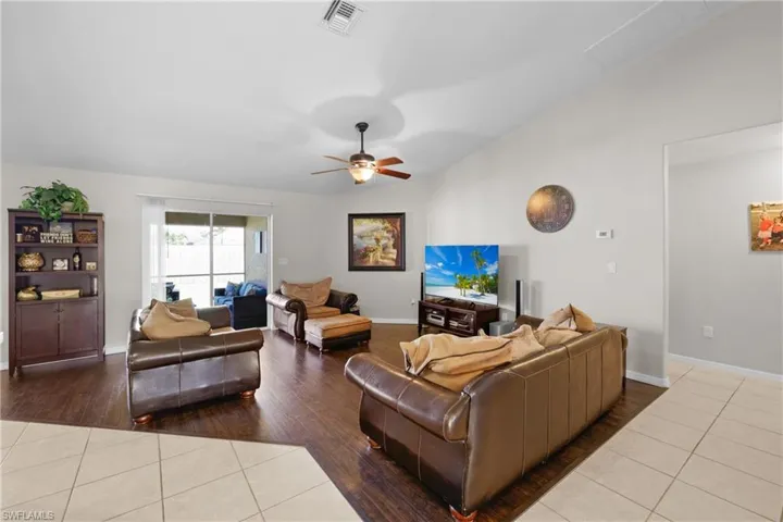 Tiled living room featuring lofted ceiling and ceiling fan