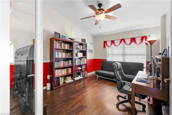 Home office with vaulted ceiling, ceiling fan, and hardwood / wood-style flooring