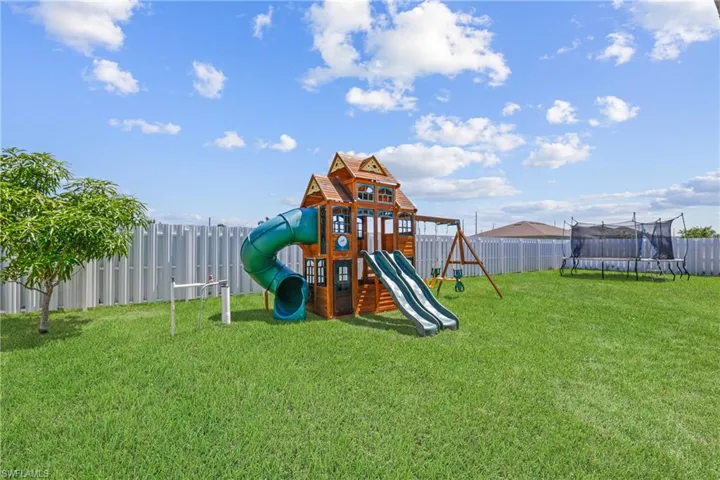 View of play area with a lawn and a trampoline