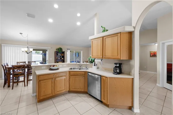 Kitchen featuring sink, kitchen peninsula, stainless steel dishwasher, and light tile floors