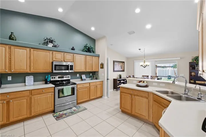 Kitchen featuring stainless steel appliances, decorative light fixtures, a notable chandelier, light tile floors, and sink