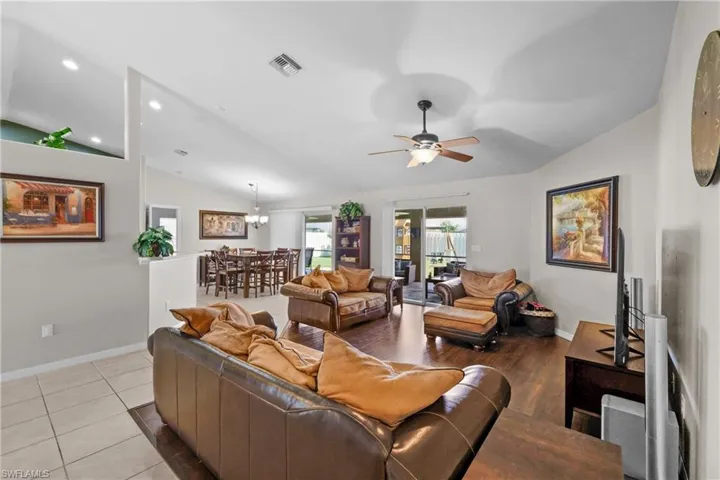 Tiled living room featuring lofted ceiling and ceiling fan with notable chandelier