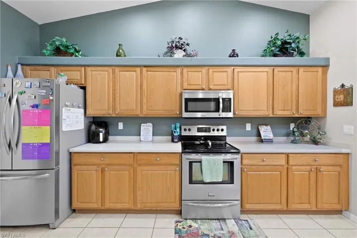 Kitchen featuring appliances with stainless steel finishes, light tile floors, and lofted ceiling