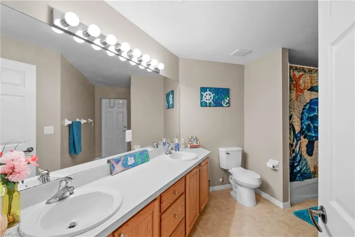 Bathroom featuring tile flooring, dual vanity, and toilet