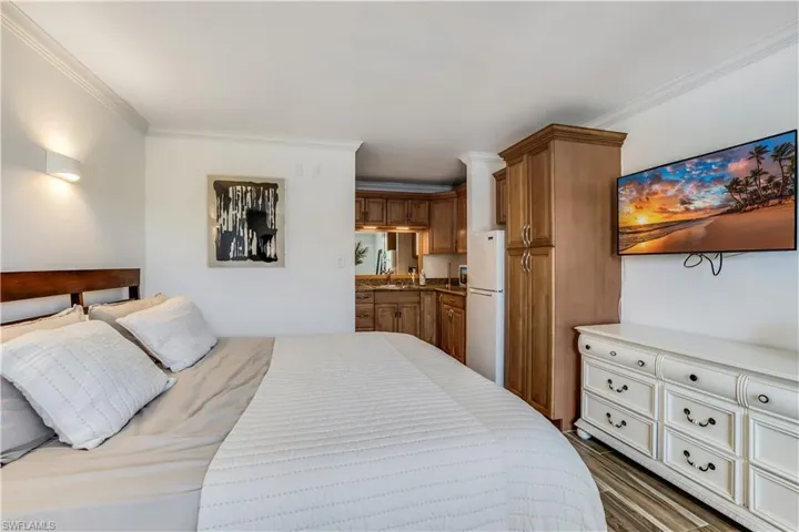 Bedroom featuring dark wood-type flooring, white refrigerator, and crown molding