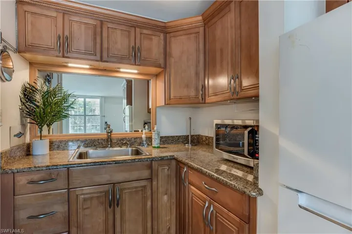 Kitchen featuring sink, dark stone countertops, and white refrigerator