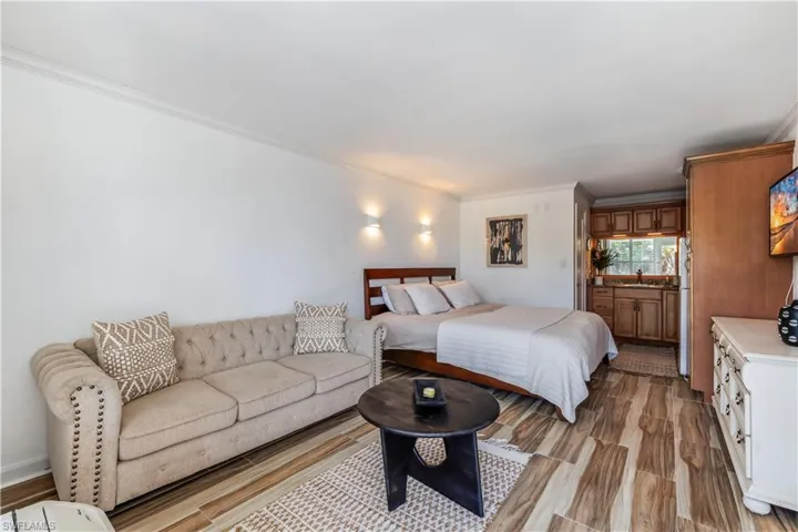 Bedroom featuring sink, refrigerator, light hardwood / wood-style flooring, and crown molding