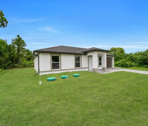 Prairie-style home with a front lawn, concrete driveway, an attached garage, and stucco siding