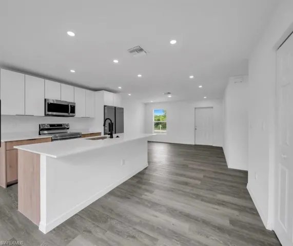 Kitchen featuring white cabinets, an island with sink, recessed lighting, appliances with stainless steel finishes, and open floor plan