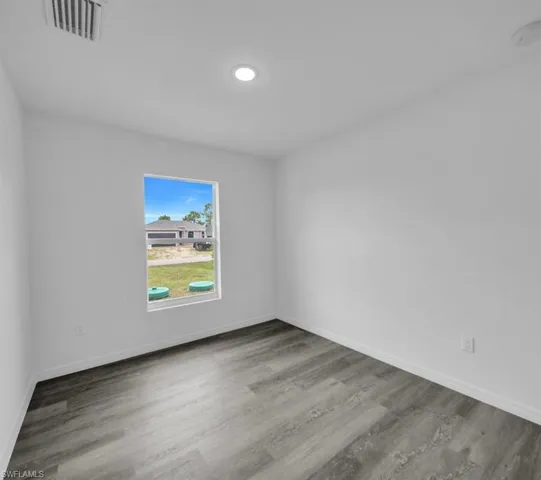 Empty room featuring light wood-type flooring and a smoke detector