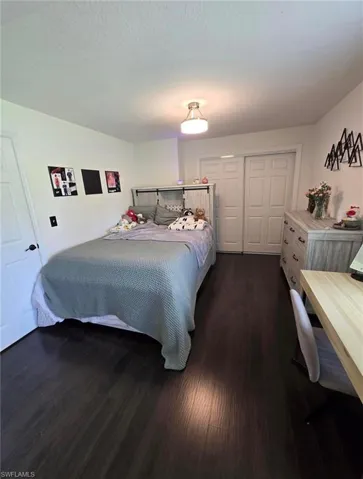 Bedroom featuring a textured ceiling, a closet, and dark hardwood / wood-style flooring