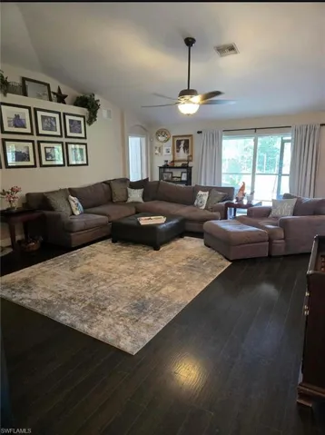 Living room featuring lofted ceiling, ceiling fan, and dark wood-type flooring