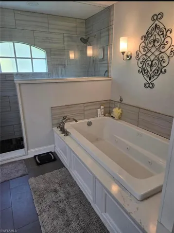 Bathroom with shower with separate bathtub and tile patterned floors