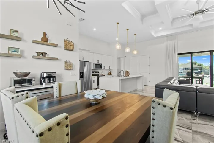 Dining room featuring ceiling fan, coffered ceiling, beam ceiling, and a high ceiling