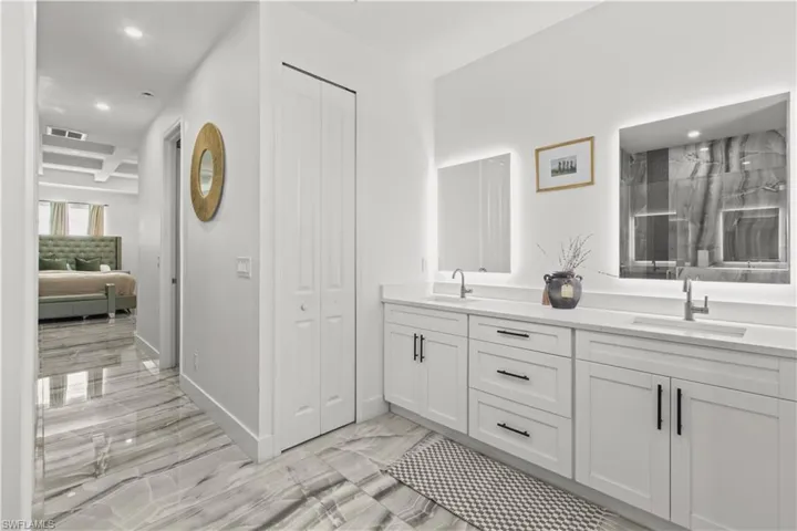Bathroom with a closet, recessed lighting, double vanity, light marble finish floors, and a marble finish shower