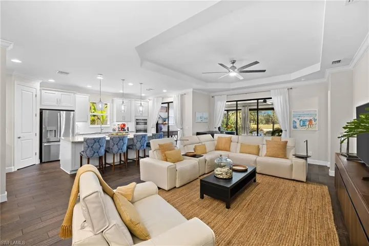 Living room featuring ornamental molding, ceiling fan, dark wood finished floors, and recessed lighting