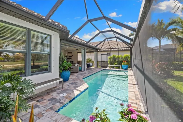 Swimming pool featuring a sunroom, glass enclosure, and a patio area