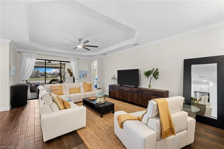 Living area with wood tiled floors, crown molding, a ceiling fan, and a tray ceiling