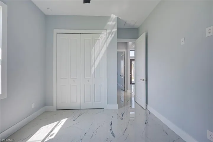 Unfurnished bedroom with light marble finish flooring and a closet