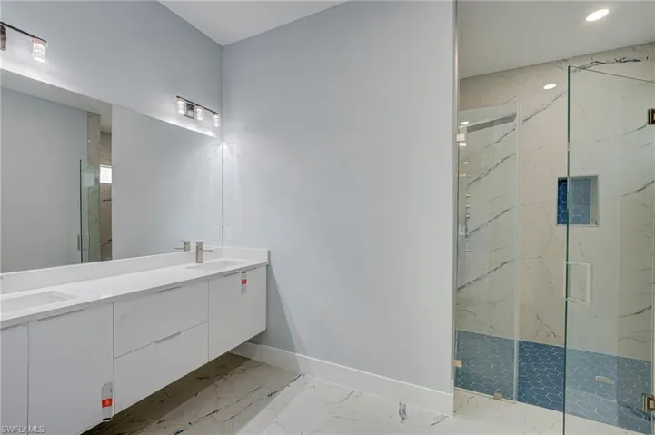 Full bath with a marble finish shower, double vanity, and light marble finish flooring