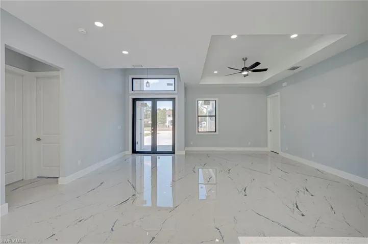 Unfurnished room with french doors, recessed lighting, a raised ceiling, light marble finish flooring, and a ceiling fan