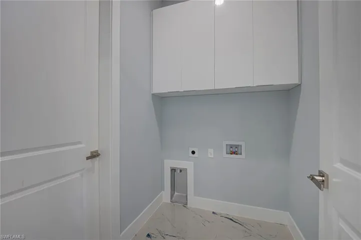 Laundry room with washer hookup, electric dryer hookup, light marble finish flooring, and cabinet space