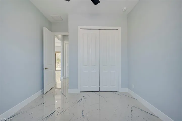 Unfurnished bedroom with a closet, a ceiling fan, and light marble finish floors