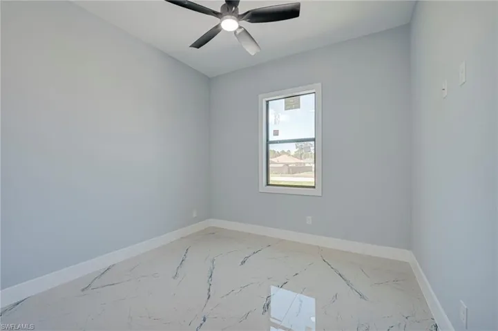 Unfurnished room featuring ceiling fan and light marble finish flooring