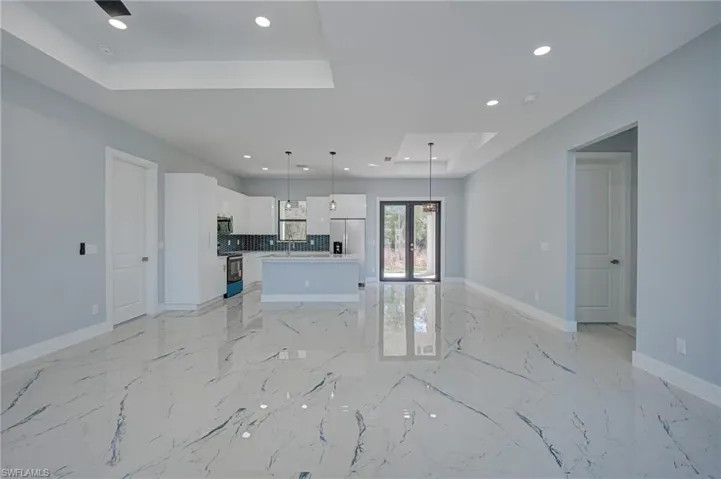 Unfurnished living room featuring a raised ceiling and recessed lighting