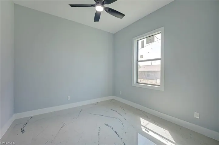 Unfurnished room with light marble finish flooring and a ceiling fan