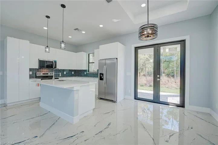 Kitchen with white cabinets, stainless steel appliances, modern cabinets, and a center island with sink