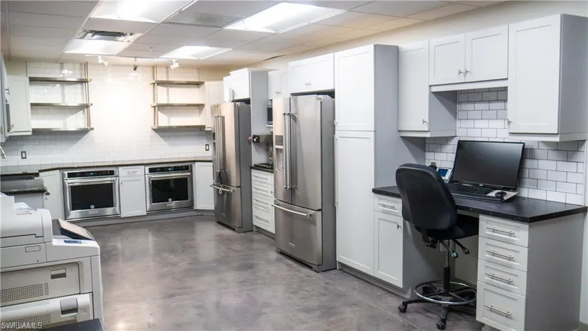 Kitchen with open shelves, stainless steel appliances, dark countertops, and decorative backsplash