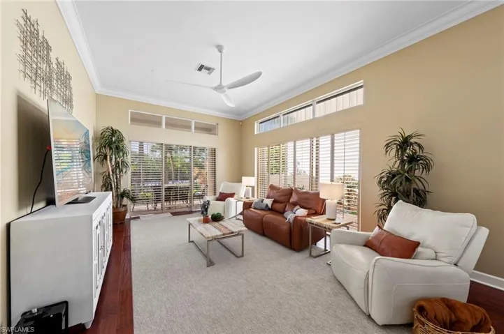 Living area with crown molding, a ceiling fan, and dark wood-type flooring