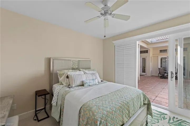 Bedroom with light tile patterned floors, ceiling fan, and french doors to courtyard