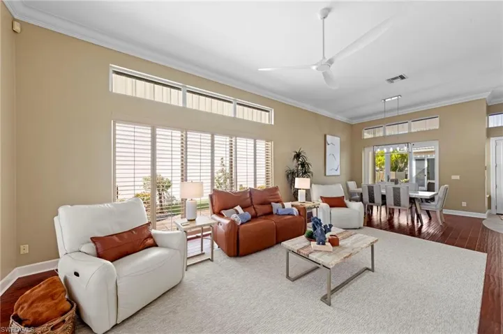 Living area featuring ornamental molding, dark wood-style flooring, and ceiling fan