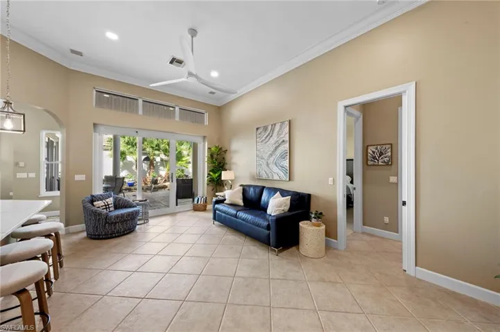 Living room with light tile patterned flooring, ceiling fan, arched walkways, recessed lighting, and ornamental molding
