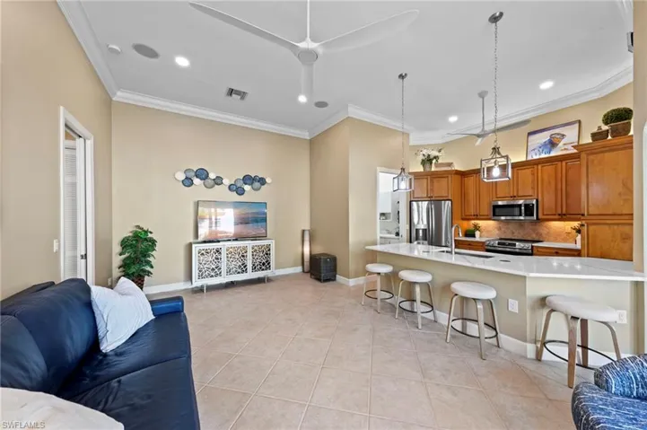 Kitchen featuring open floor plan, brown cabinetry, a kitchen breakfast bar, decorative light fixtures, and appliances with stainless steel finishes