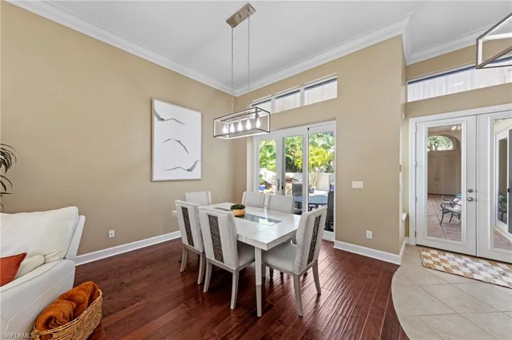 Dining room with french doors, dark wood-type flooring, and ornamental molding