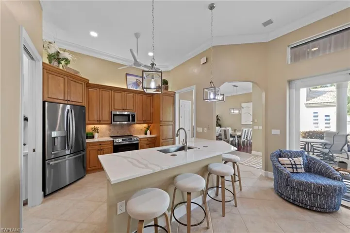 Kitchen with stainless steel appliances, pendant lighting, light tile patterned flooring, a kitchen breakfast bar, and arched walkways